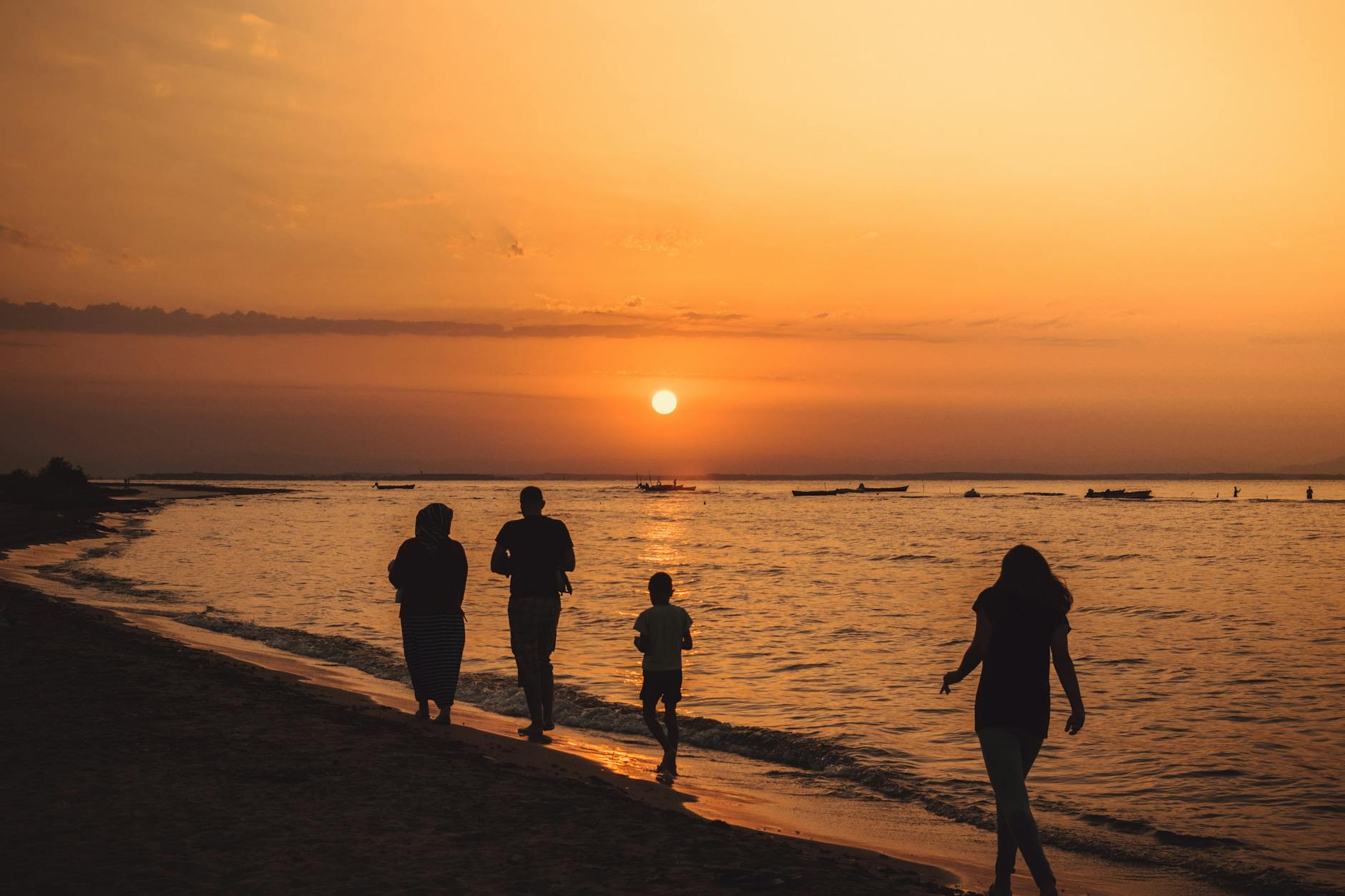 silhouette of people walking on seashore during sunset