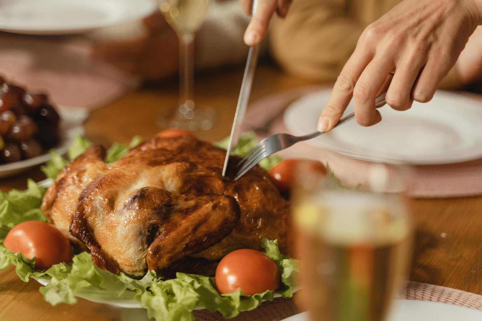 a person holding stainless steel fork and knife slicing cooked meat