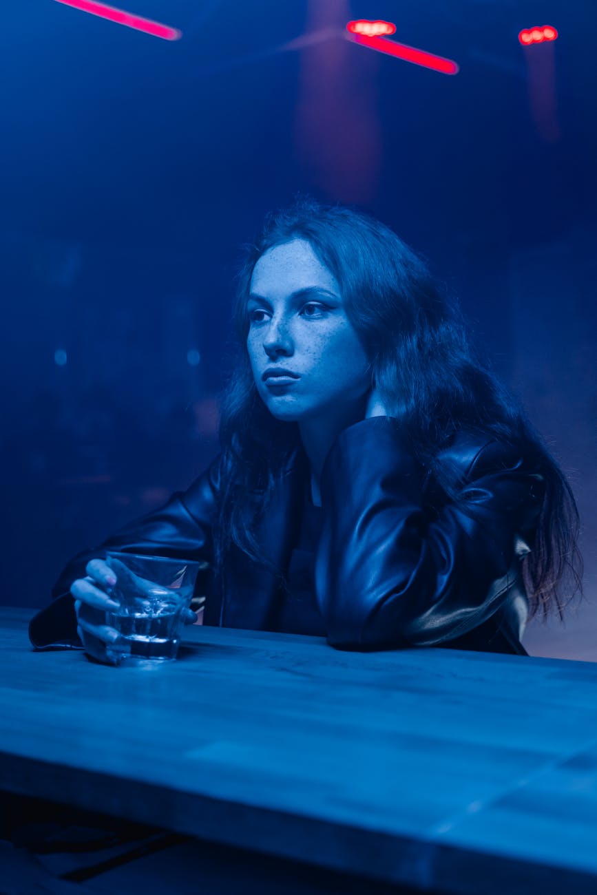 woman in a leather jacket holding a glass of an alcoholic drink